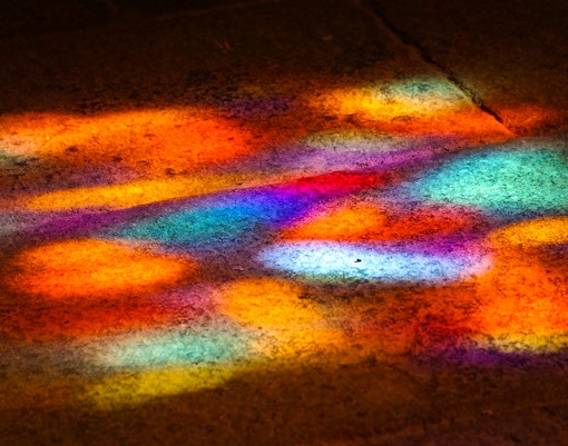 Reflections of stained glass at Sainte-Chapelle create a kaleidoscope effect on the floor.