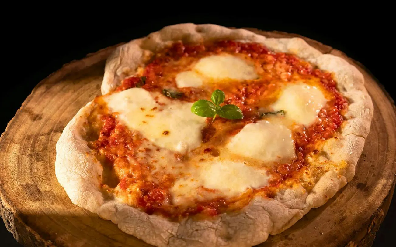 Pizza with tomato sauce and mozzarella on a wooden board, Orosei workshop, Nuoro.