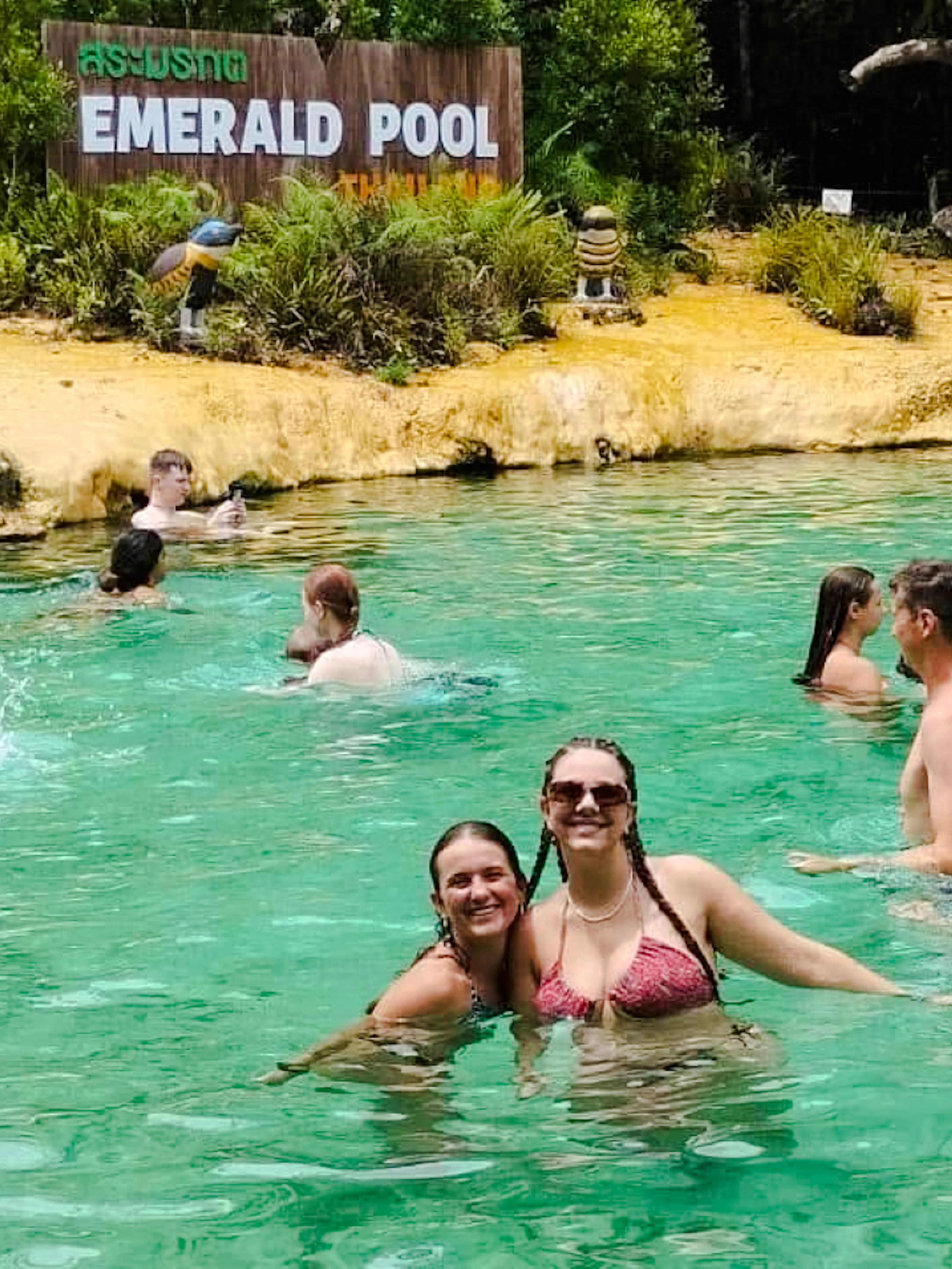 Visitors enjoying the water at Emerald Pool, Krabi, surrounded by lush greenery.