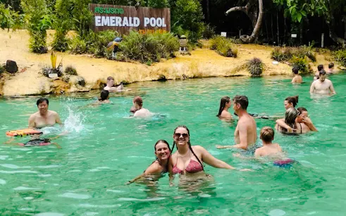 Visitors enjoying the water at Emerald Pool, Krabi, surrounded by lush greenery.