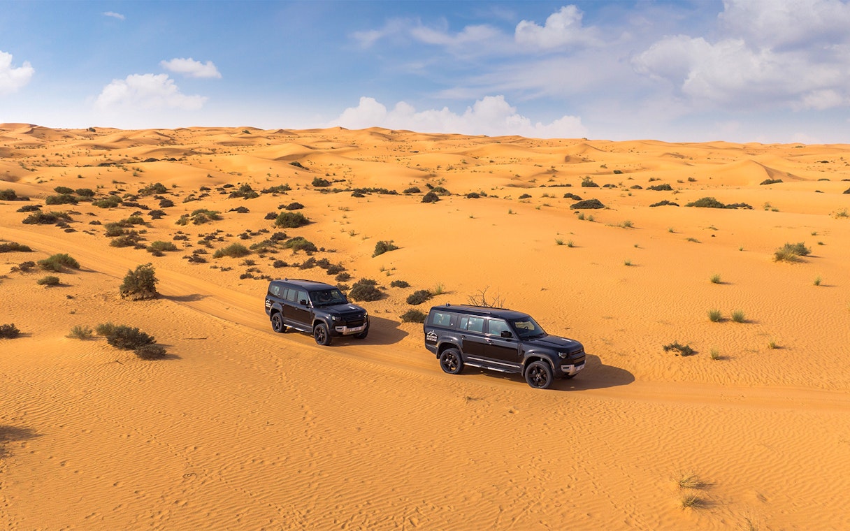 Two SUVs driving through a desert landscape, part of a premium hot air balloon experience.