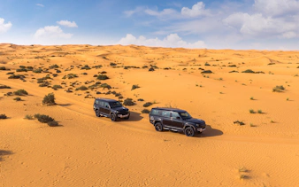 Two SUVs driving through a desert landscape, part of a premium hot air balloon experience.