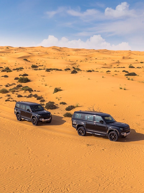Two SUVs driving through a desert landscape, part of a premium hot air balloon experience.
