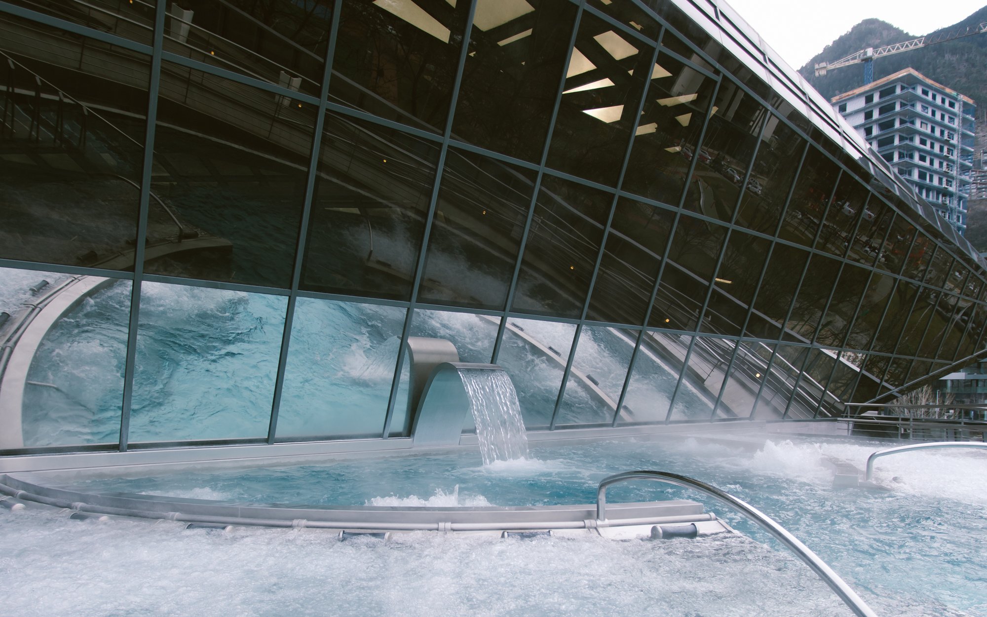 Outdoor lagoon at Caldea thermal spa with cascading water feature.