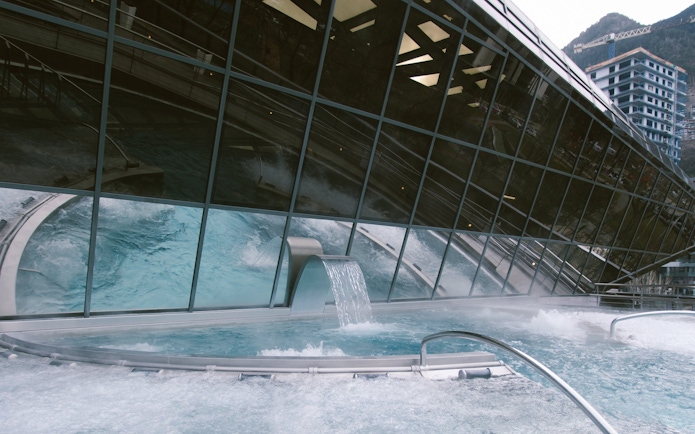 Outdoor lagoon at Caldea thermal spa with cascading water feature.