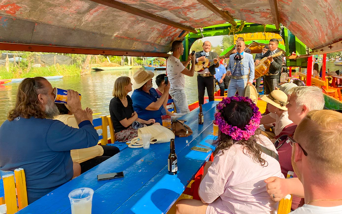 Guests enjoying live music on a Trajinera party boat in Xochimilco, Mexico.