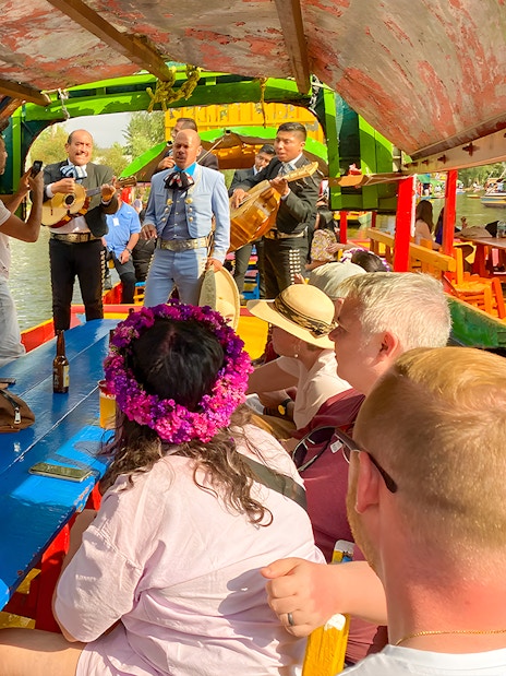 Guests enjoying live music on a Trajinera party boat in Xochimilco, Mexico.