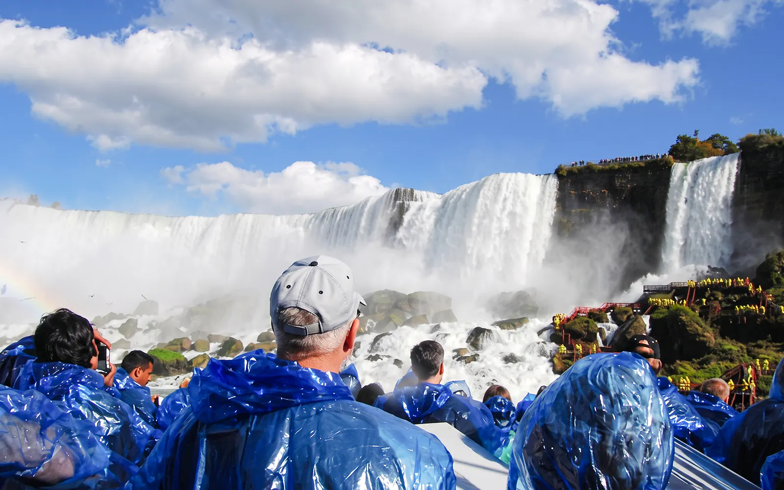 Visitors in blue ponchos viewing Niagara Falls from a boat tour in New York.