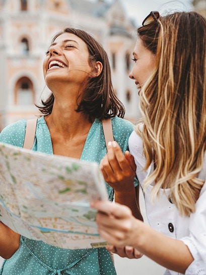 Tourists exploring a city with a map in front of historic architecture.