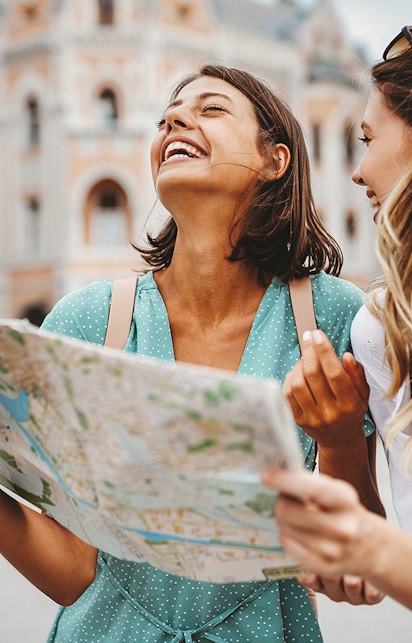 Tourists exploring a city with a map in front of historic architecture.