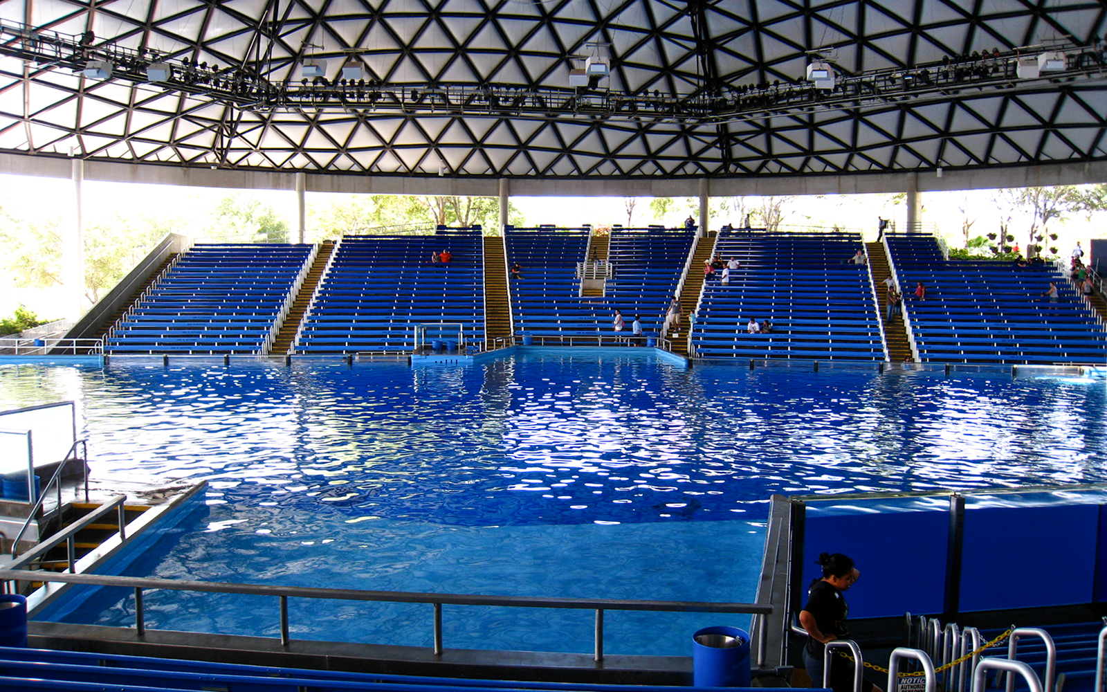 SeaWorld San Antonio amphitheater with empty blue seats and large pool.