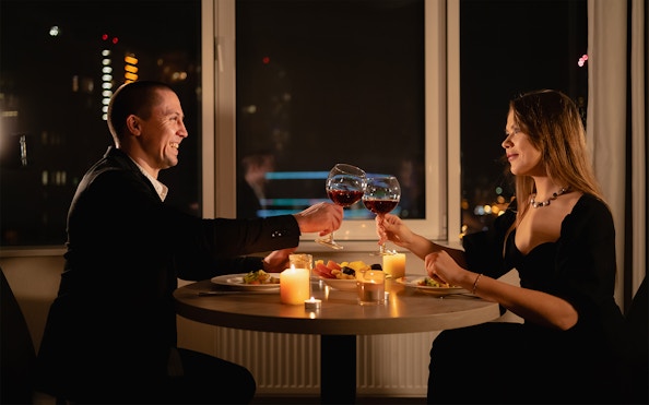 Couple toasting wine glasses during candlelight dinner on Budapest Danube River cruise.