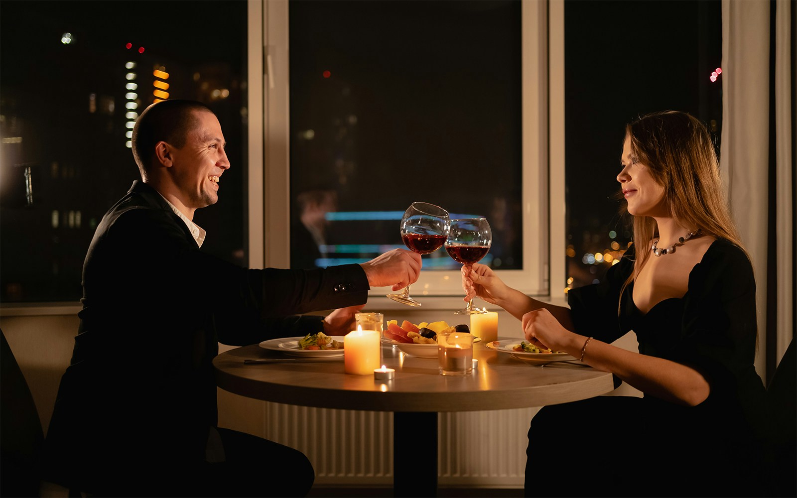 Couple enjoying candlelight dinner on Budapest Danube River cruise with city lights in the background.