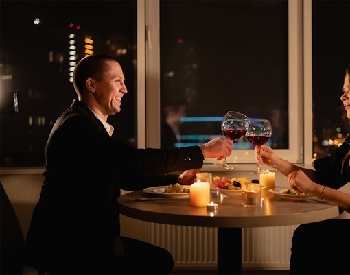 Couple toasting wine glasses during candlelight dinner on Budapest Danube River cruise.