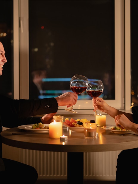 Couple toasting wine glasses during candlelight dinner on Budapest Danube River cruise.