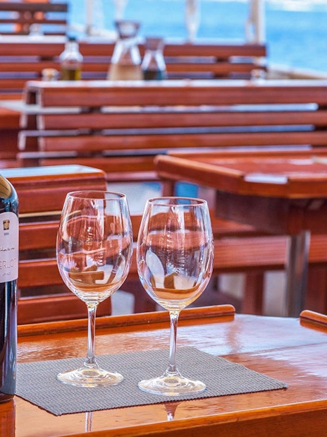 Wine bottles and glasses on a wooden table during Dubrovnik Elaphite Islands boat tour.