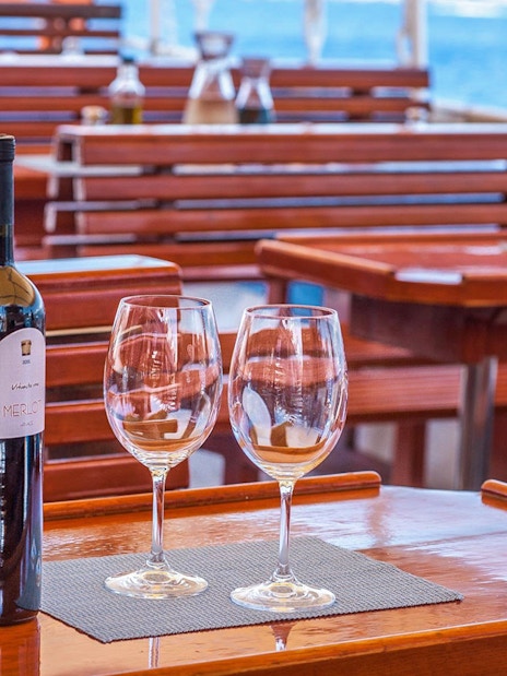 Wine bottles and glasses on a wooden table during Dubrovnik Elaphite Islands boat tour.