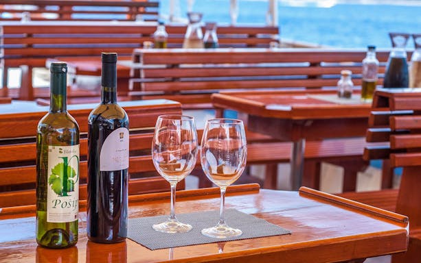 Wine bottles and glasses on a wooden table during Dubrovnik Elaphite Islands boat tour.
