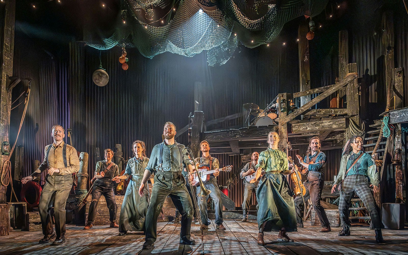 Cast performing on stage in "The Curious Case of Benjamin Button - The Musical" with instruments.