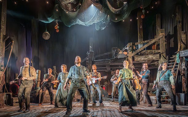 Cast performing on stage in "The Curious Case of Benjamin Button - The Musical" with instruments.