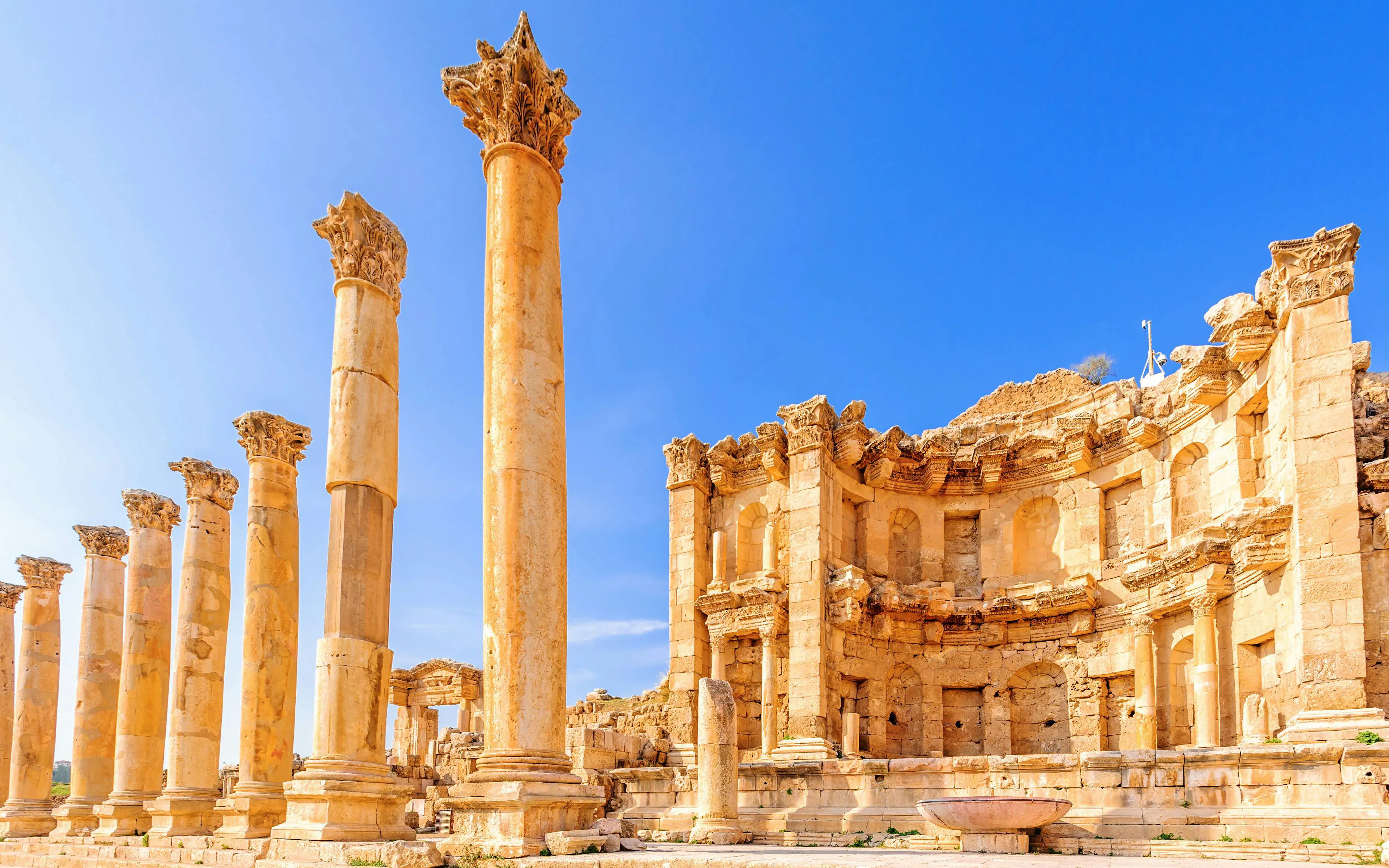Nymphaeum ruins with columns in Jerash, Jordan under clear blue sky.