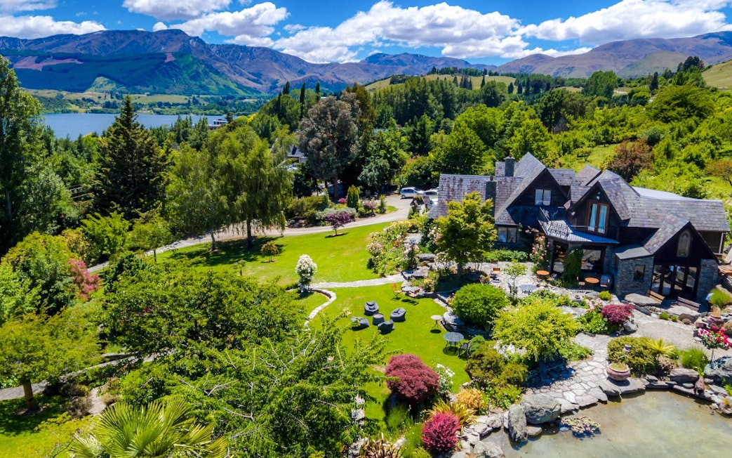 Aerial view of a vineyard estate in Queenstown with lush gardens and mountain backdrop.