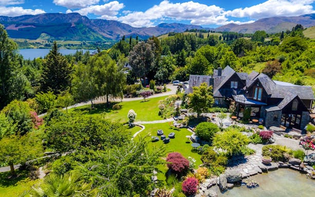 Aerial view of a vineyard estate in Queenstown with lush gardens and mountain backdrop.