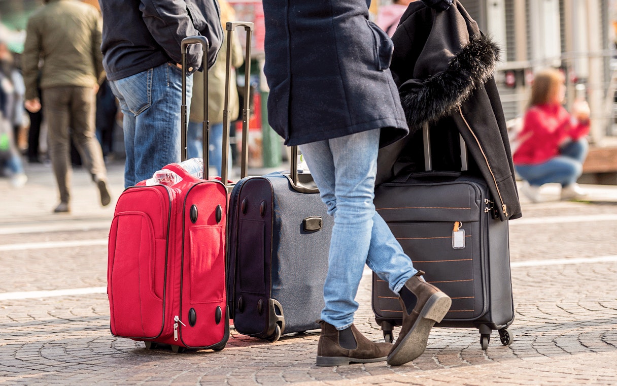 Tourists standing with luggage on a city street.