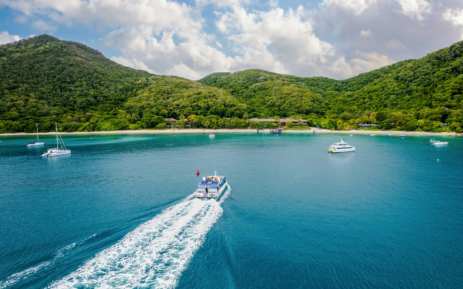 Boat approaching Fitzroy Island with lush hills and clear blue water.