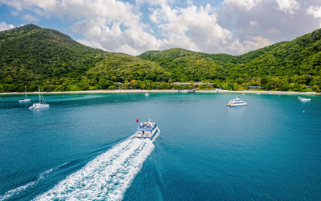 Boat approaching Fitzroy Island with lush hills and clear blue water.