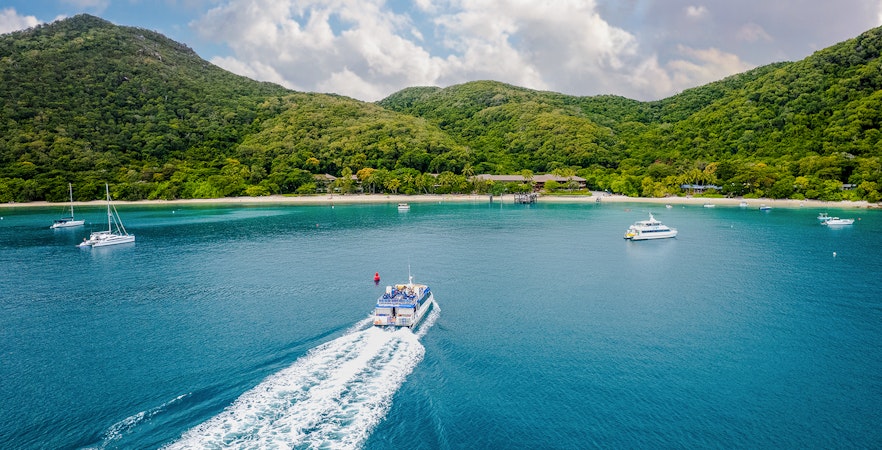 Boat approaching Fitzroy Island with lush hills and clear blue water.