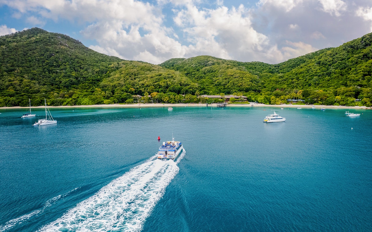 Boat approaching Fitzroy Island with lush hills and clear blue water.
