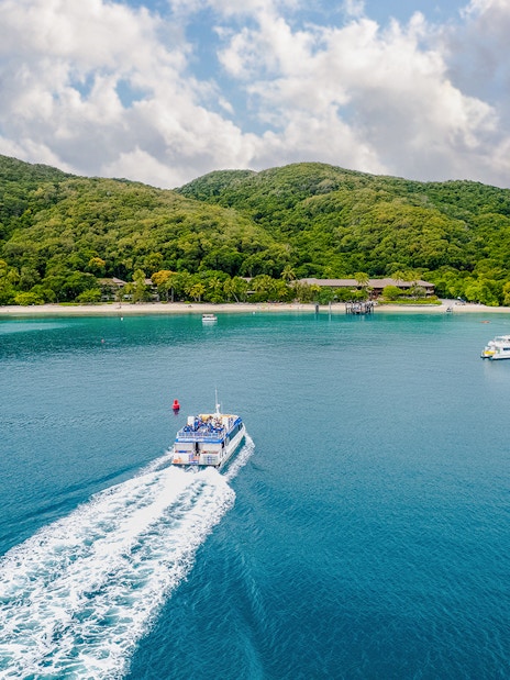 Boat approaching Fitzroy Island with lush hills and clear blue water.