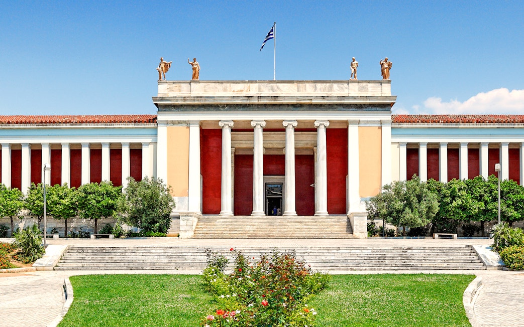 Exterior of Athens National Archaeological Museum with columns and statues.