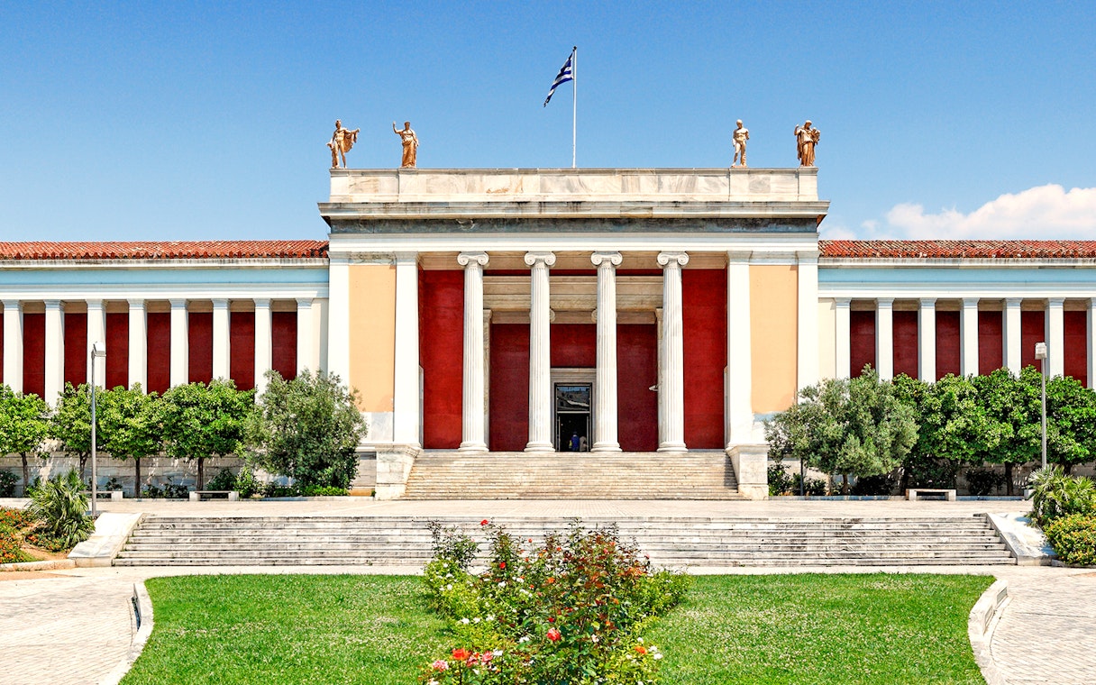 Exterior of Athens National Archaeological Museum with columns and statues.