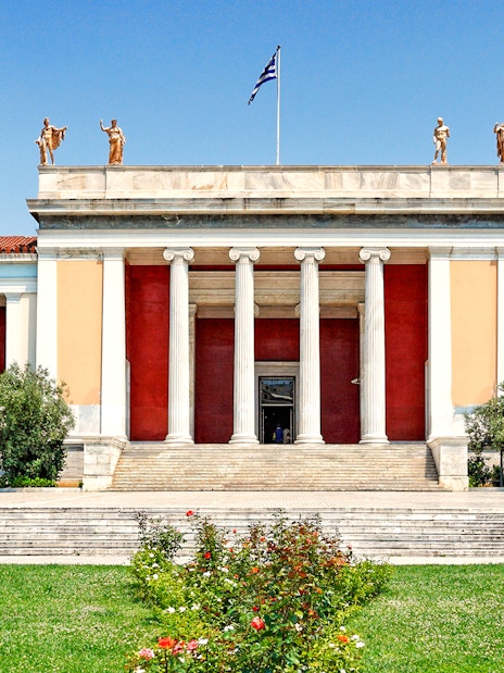 Exterior of Athens National Archaeological Museum with columns and statues.