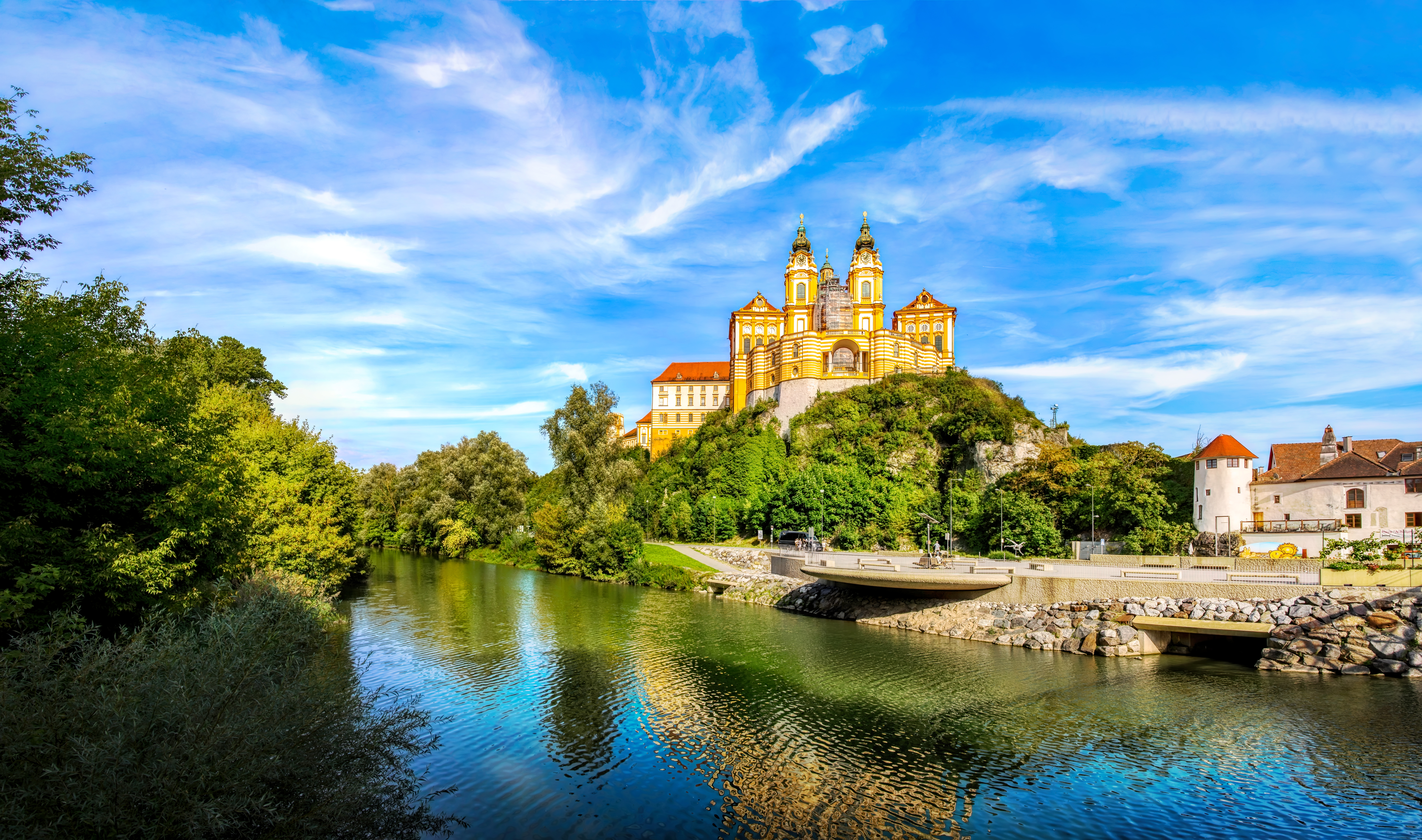Melk Abbey overlooking the Danube River in Melk, Austria, surrounded by lush greenery.