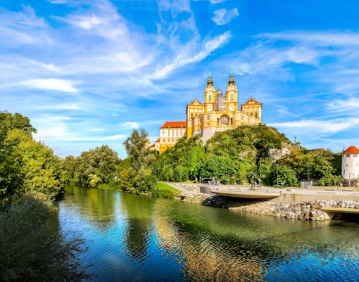 Melk Abbey overlooking the Danube River in Melk, Austria, surrounded by lush greenery.