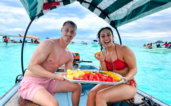 Couple enjoying fresh fruit on a boat during Mnemba Island tour, Zanzibar.
