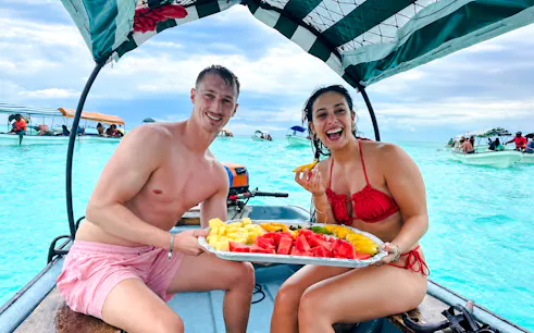Couple enjoying fresh fruit on a boat during Mnemba Island tour, Zanzibar.