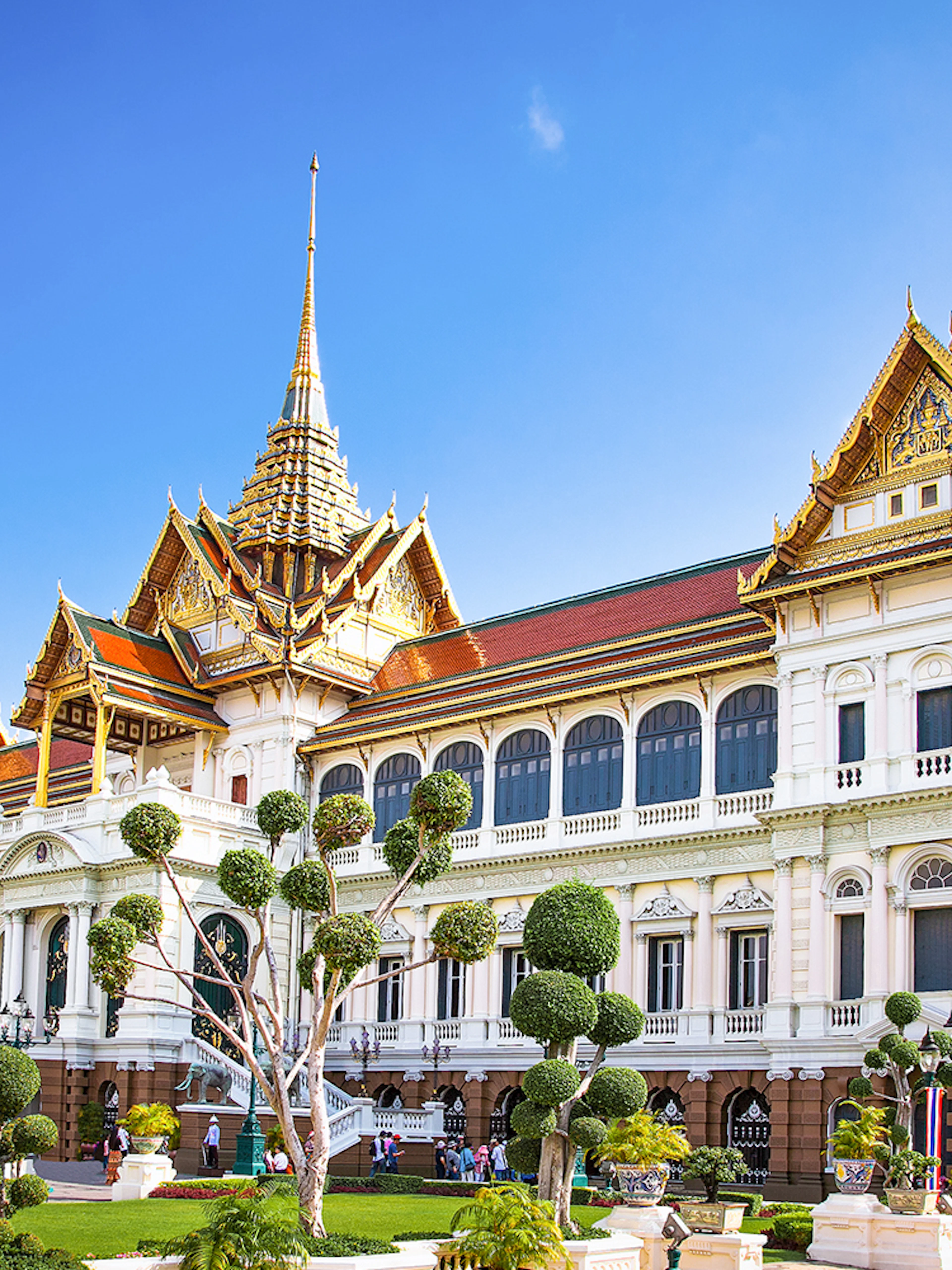 Grand Palace in Bangkok with ornate architecture and manicured gardens.