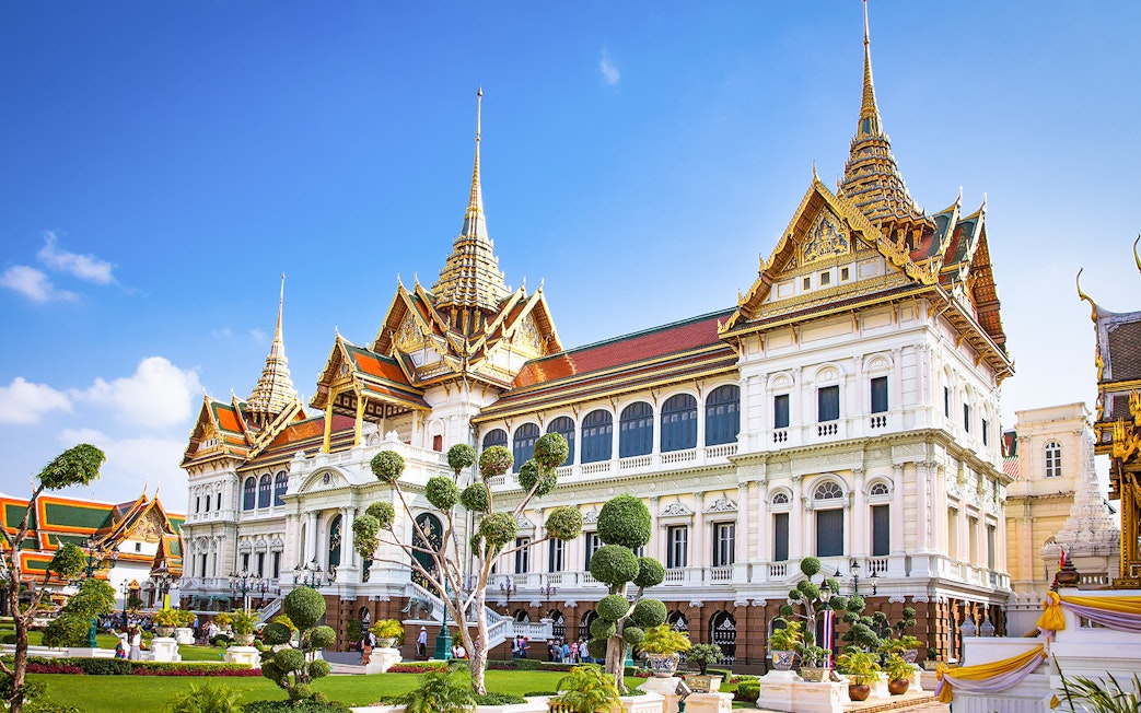 Grand Palace in Bangkok with ornate architecture and manicured gardens.