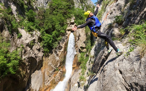 Canyoneer rappelling beside waterfall on Cetina River Extreme Canyoning Adventure.