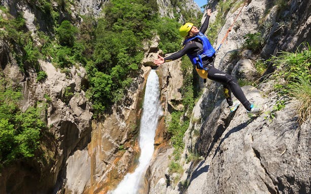 Canyoneer rappelling beside waterfall on Cetina River Extreme Canyoning Adventure.