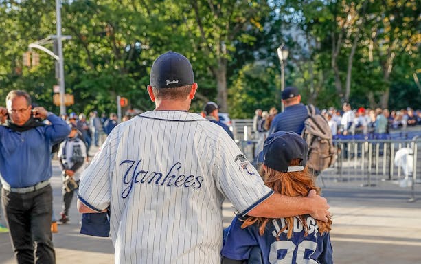 Fans in Yankees jerseys walking towards the stadium for the New York Yankees vs Washington Nationals game.
