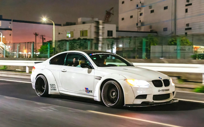 White sports car drifting on Tokyo street at night.