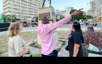 Local guide leading a walking tour in Dar es Salaam Old Town, pointing out historical landmarks.