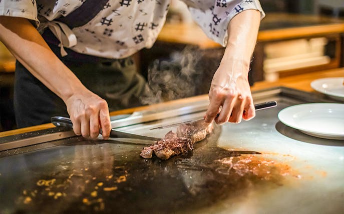 Chef grilling meat on teppanyaki grill during Tokyo street food tour in Shibuya.