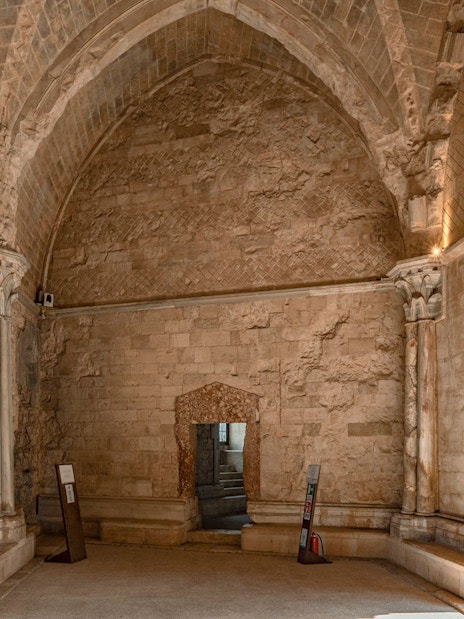 Throne room interior of Castel del Monte, Andria, featuring stone walls and arched doorway.
