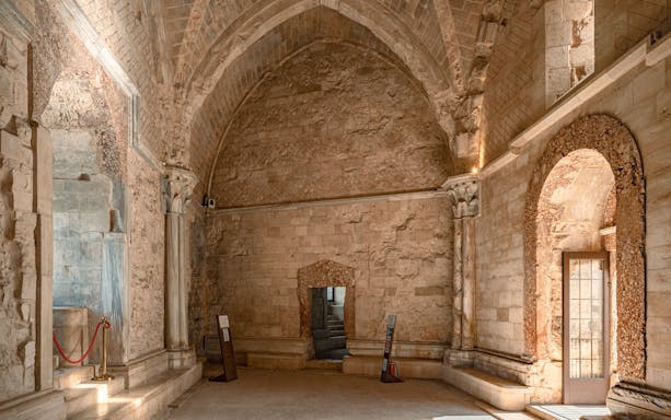 Throne room interior of Castel del Monte, Andria, featuring stone walls and arched doorway.